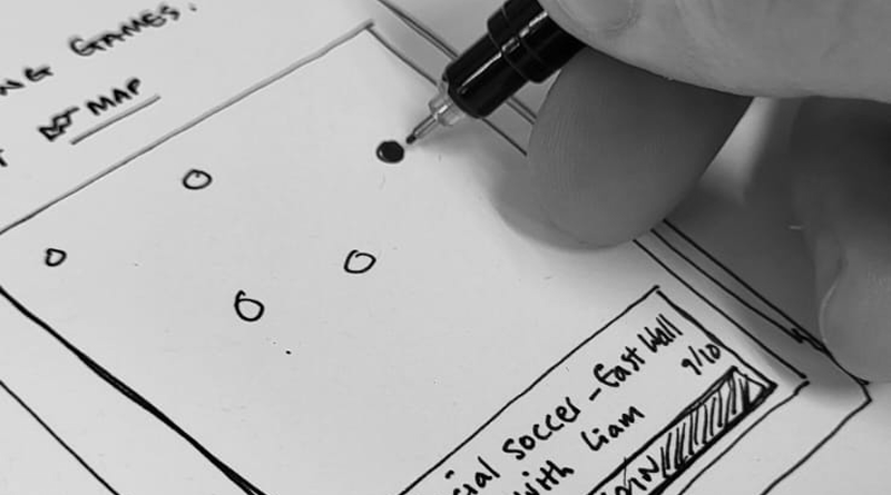 Hand holding pencil drawing wireframe/sketch